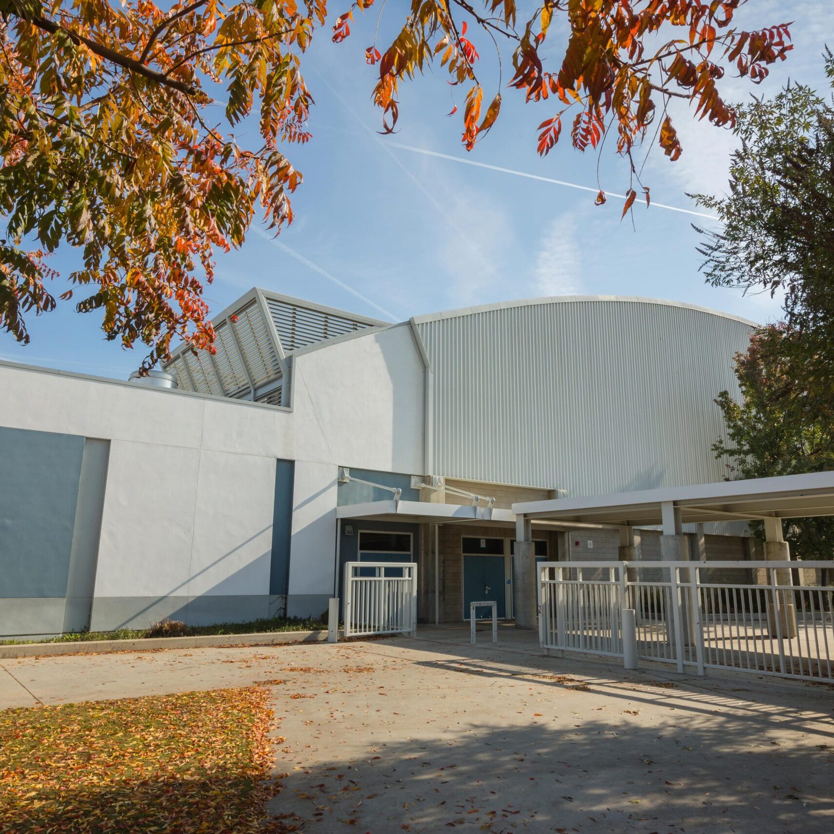 Clovis east exterior leading into the gymnasium surrounded by trees and clean gates leading into the building with concrete grounds on a fall afternoon